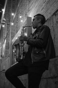 Black and white photo of a saxophonist playing in the street at night in Cuenca, Ecuador.